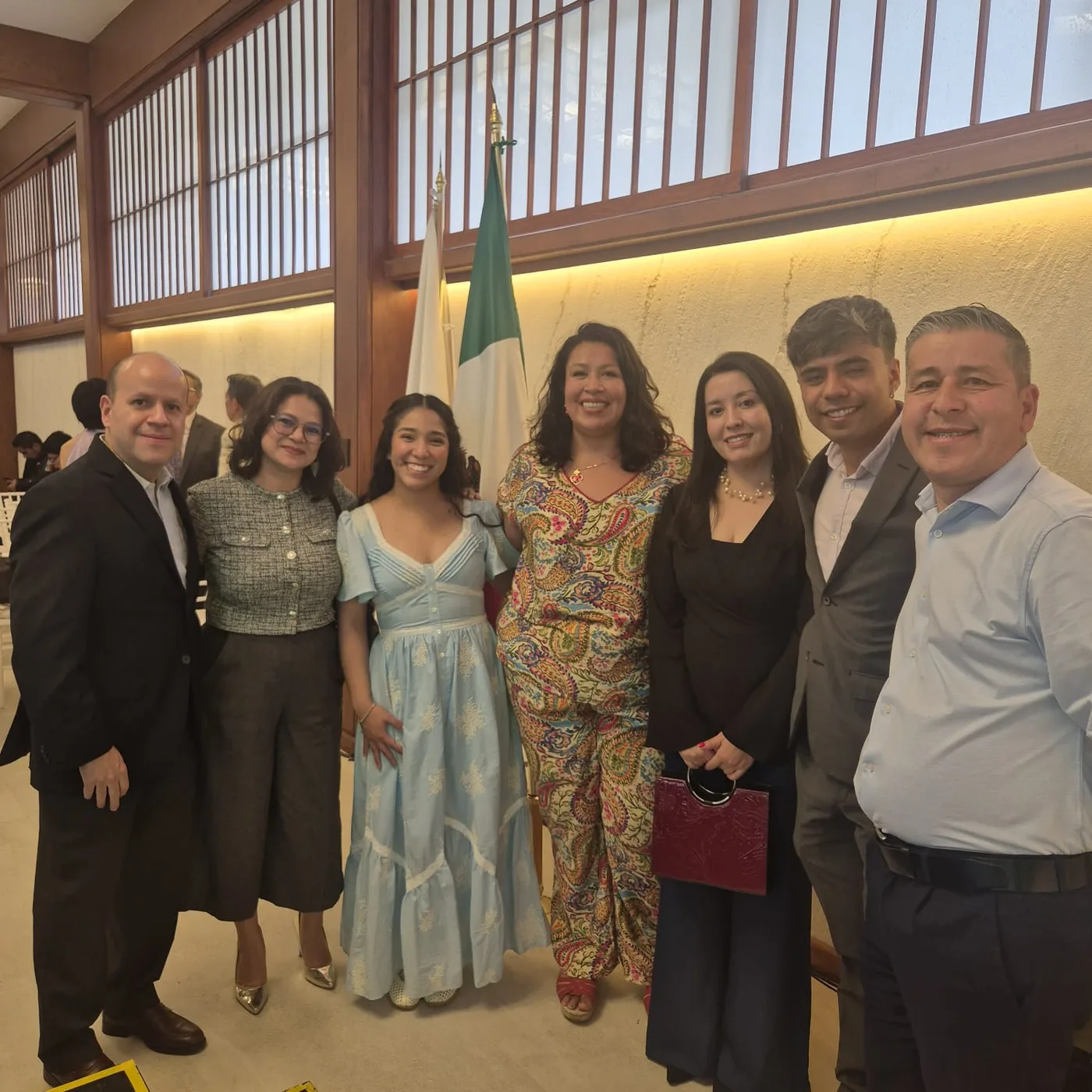 Grupo de invitados en la presentación del libro ¡Gambare! junto a la bandera de México