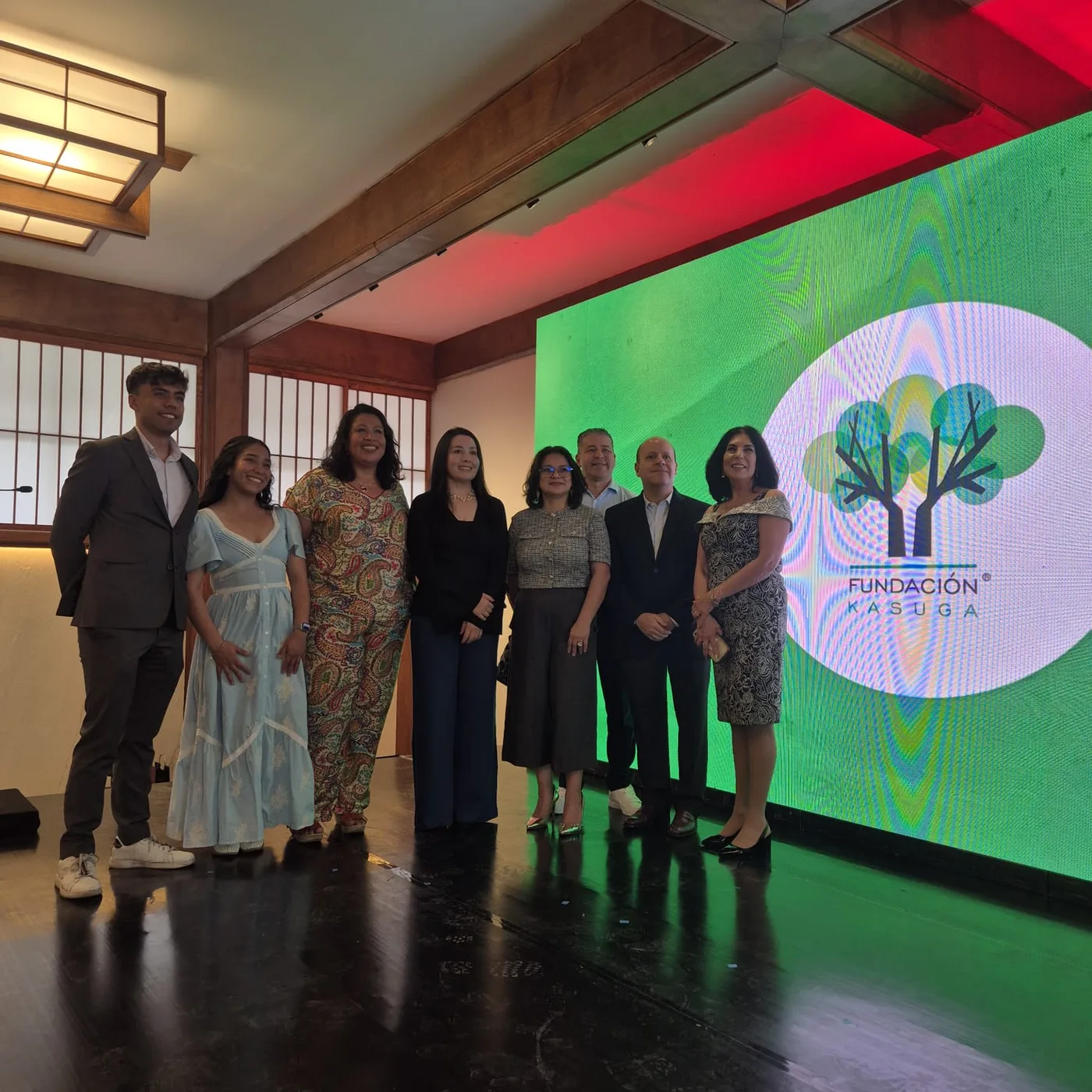 Grupo de invitados frente a la pantalla de Fundación Kasuga en la presentación del libro