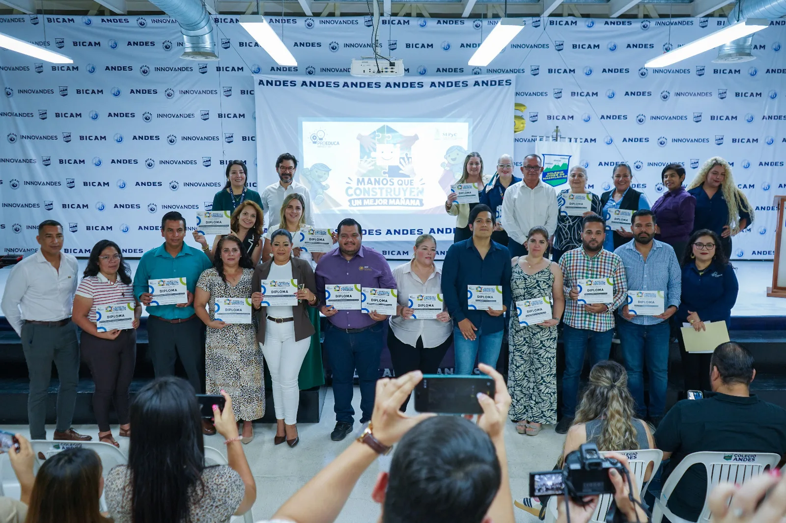 Grupo de directivas y representantes de escuelas con su diploma en la ceremonia "Manos que Construyen un Mejor Mañana"