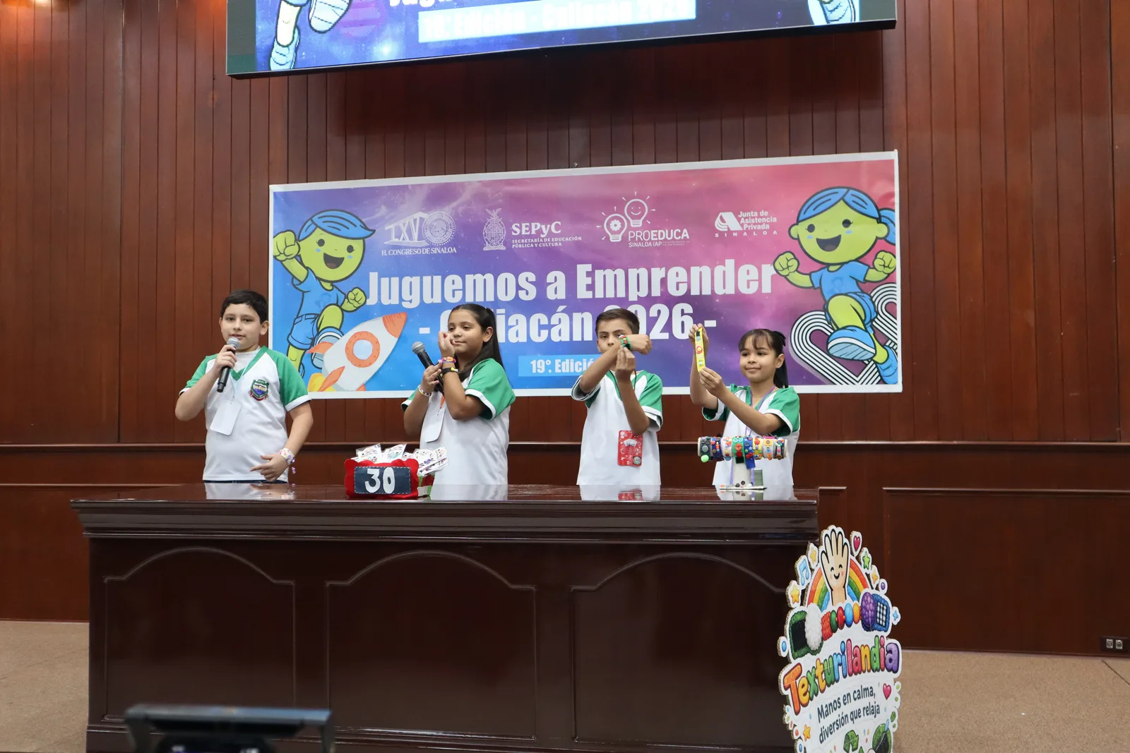 Estudiantes presentan su proyecto emprendedor ante el público en el escenario de Juguemos a Emprender