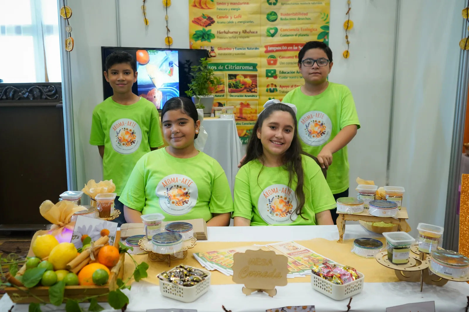 Niñas y niños del equipo Aroma-Arte en su stand de productos cítricos artesanales